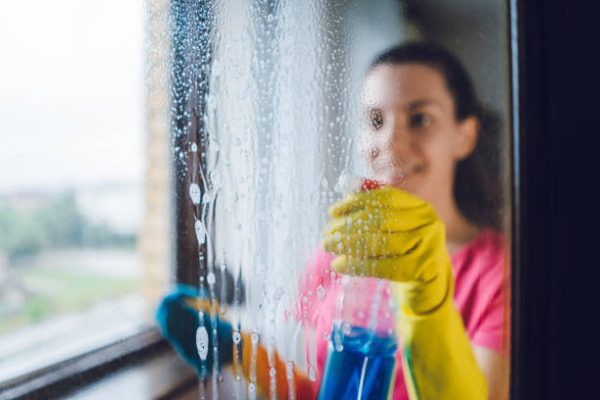 Young woman wiping windows at home Young woman wiping windows at home