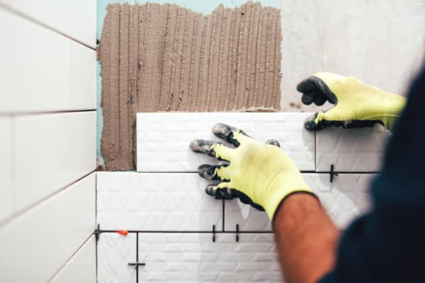 tilesgrout industrial construction worker installing small ceramic tiles on bathroom walls and applying mortar with trowel